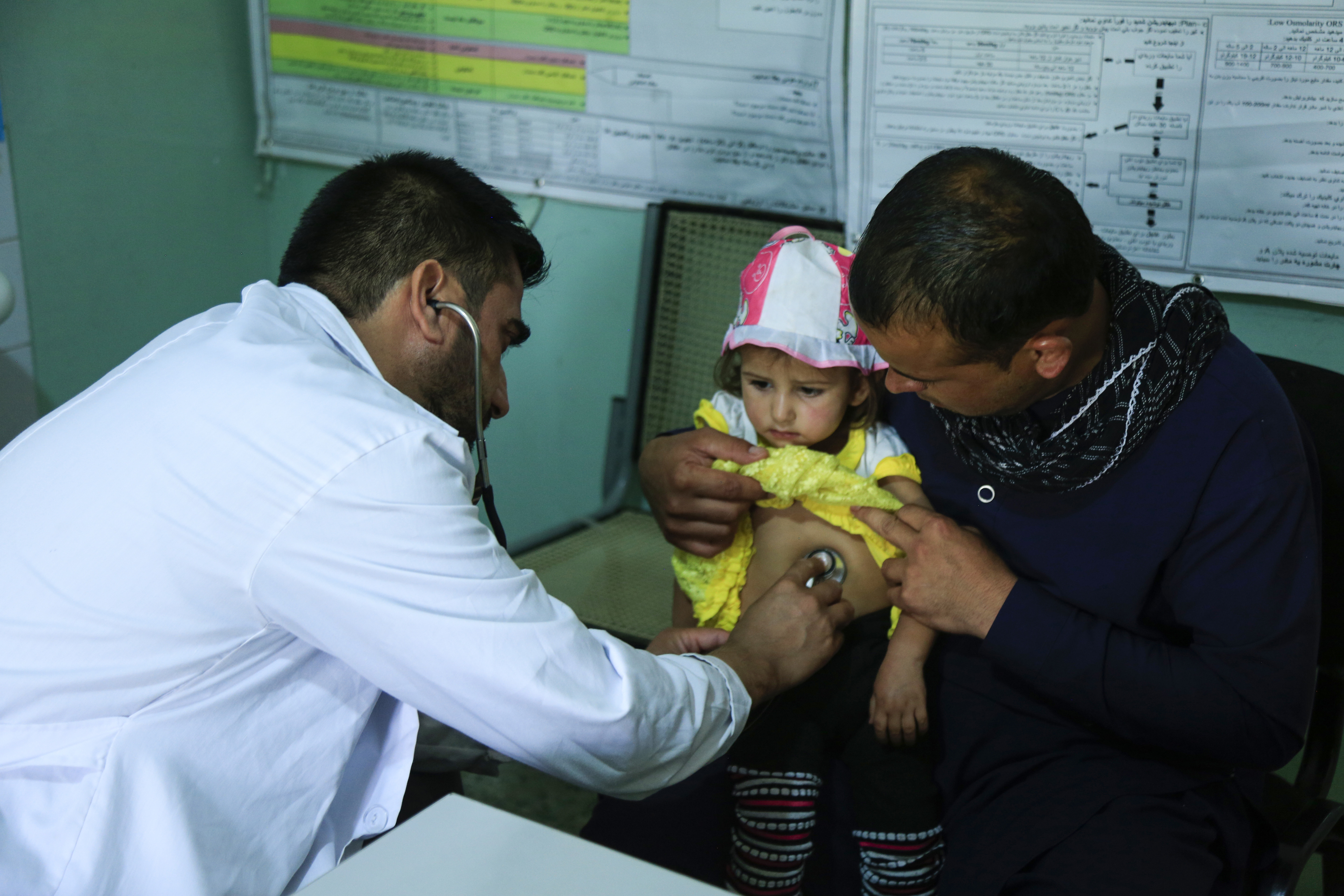 Doctor treating baby who is held by father