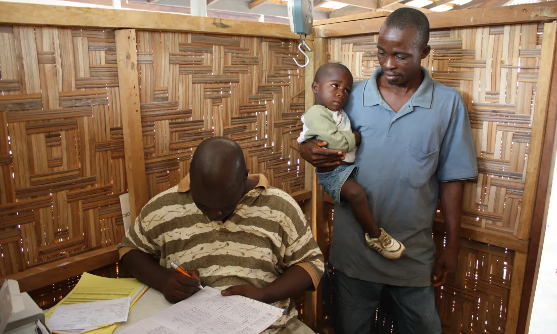 man holding child watch another man writing 