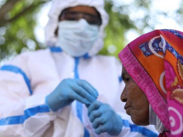 Photo showing health worker in protective gear and mask with woman wearing colourful head covering