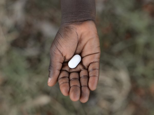 child's hand holding a pill