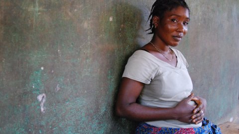 Pregnant woman sitting against a wall