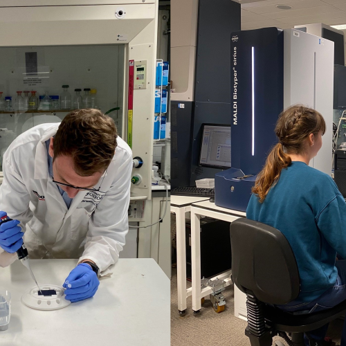 Photo of lab workers at computer and using a pipette