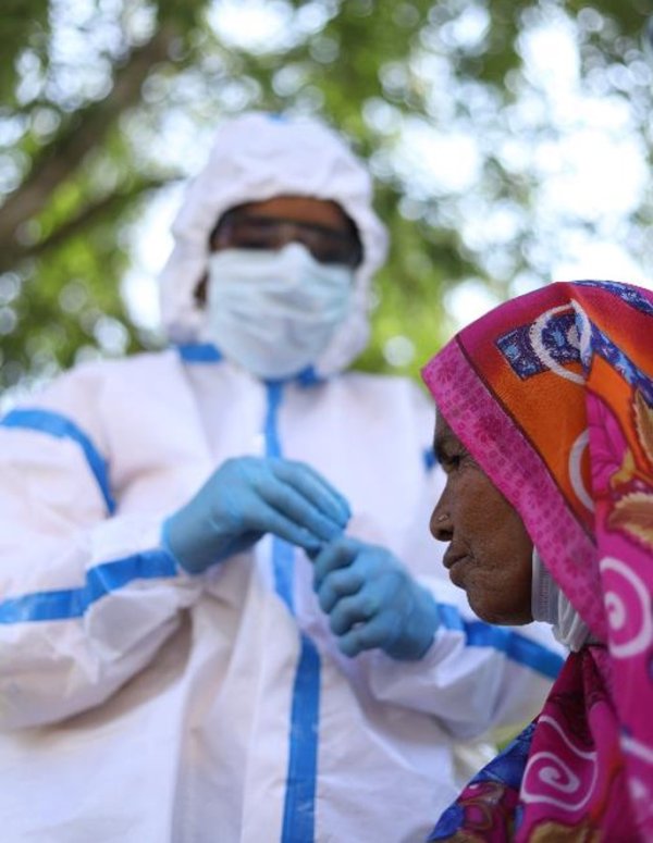 Photo showing health worker in protective gear and mask with woman wearing colourful head covering