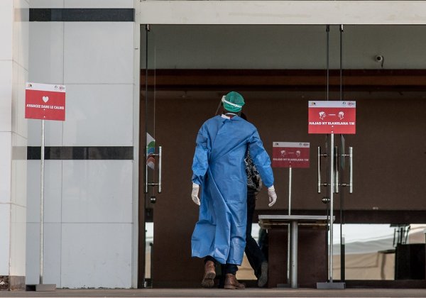 photo of man in PPE in front of red signs