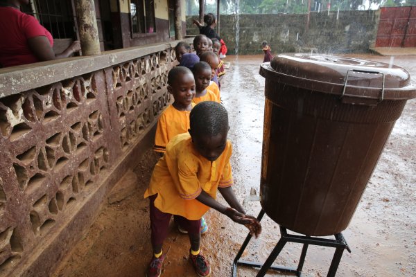 Photo of smiling schoolchildren in uniform waiting in line for water 