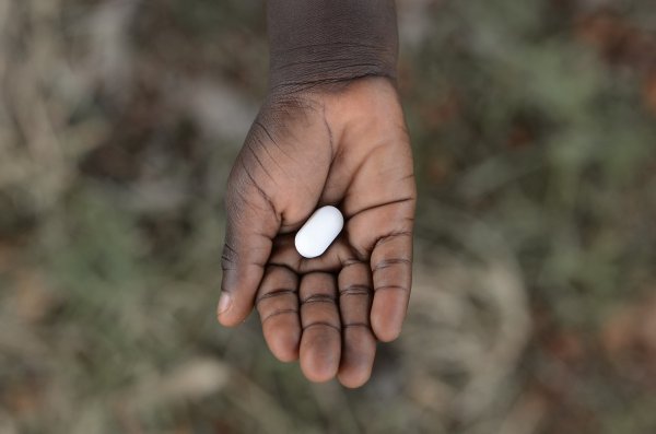 child's hand holding a pill