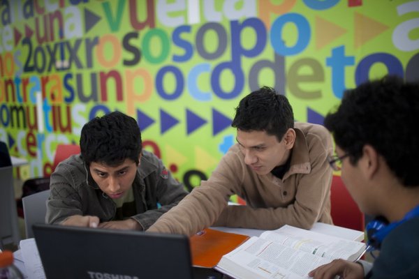 Photo of men looking at laptop against colourful background